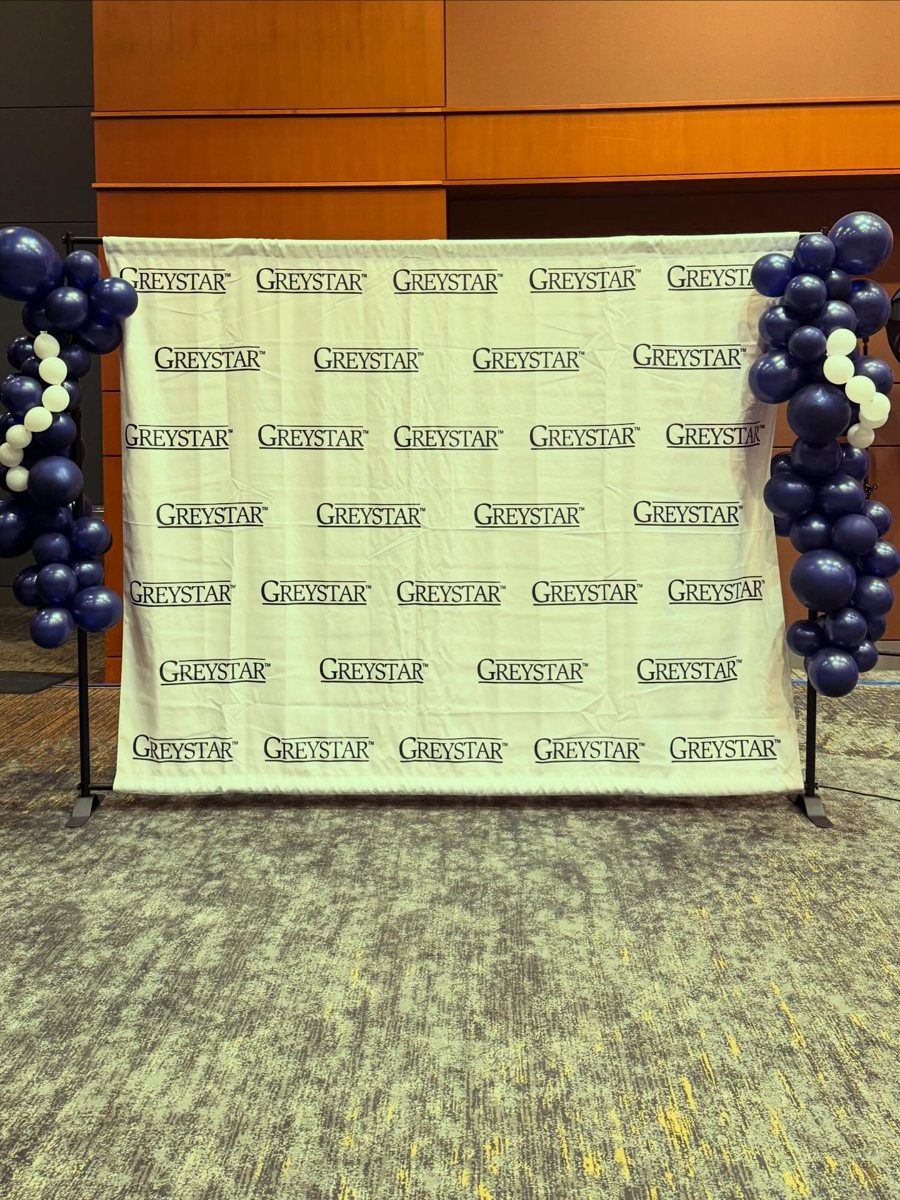 Corporate step-and-repeat backdrop framed by navy and white organic balloon garlands