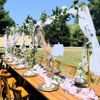 Outdoor garden tablescape with greenery arch, pink runners, florals and vintage china
