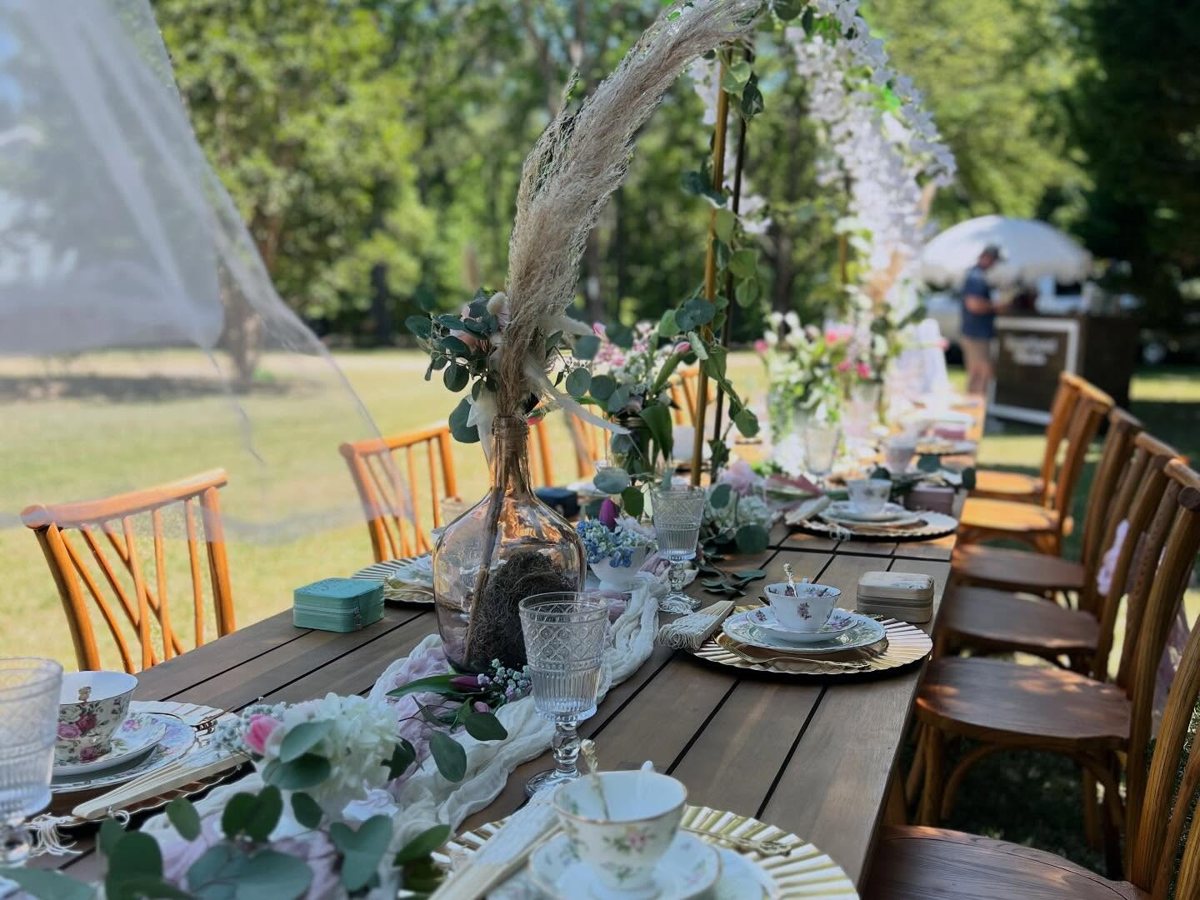Garden tea party table with crystal goblets, vintage teacups, gold chargers and pampas centerpiece