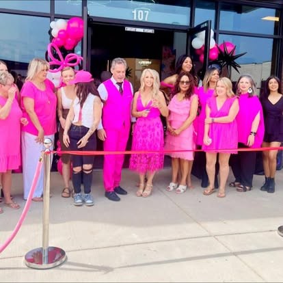 Grand opening ribbon cutting with pink balloons and guests dressed in pink