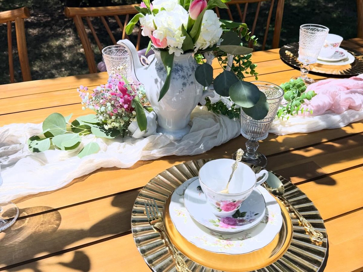 Rose-print teacup and saucer on a gold ruffled charger with gold flatware and a crystal goblet